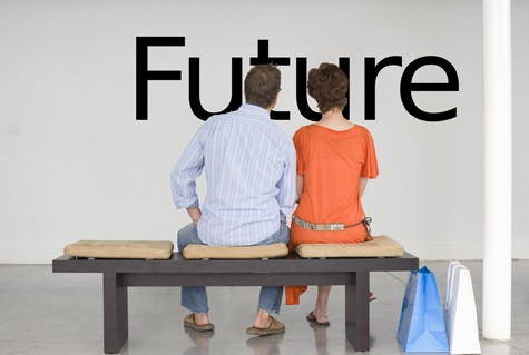 Rear view of couple seated on bench reading English text on wall